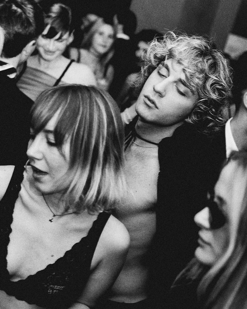 Black and white photo of people dancing closely at a crowded party during the Acido Lattico Magazine x Carnale event, captured by Wilson Ballarin.